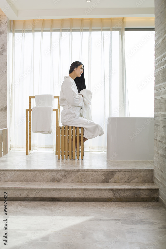 Young woman drying her hair with a towel in bathroom