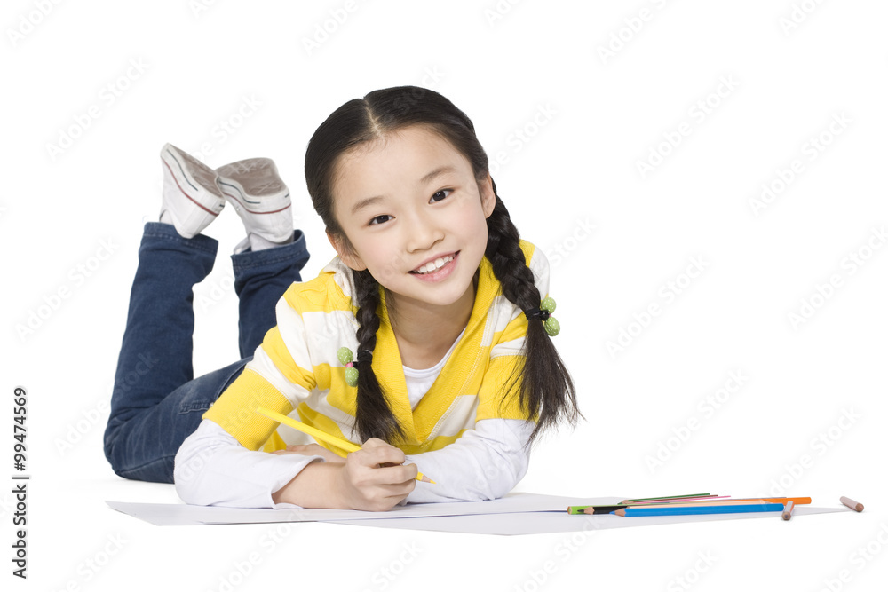 A young girl coloring while lying on the floor