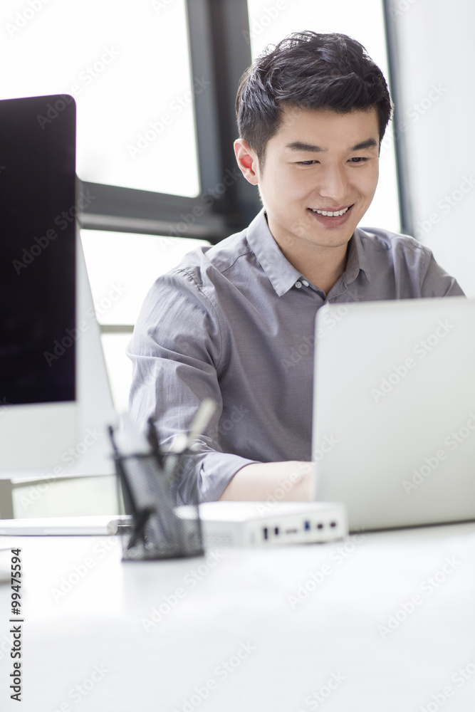 Young businessman using laptop in office