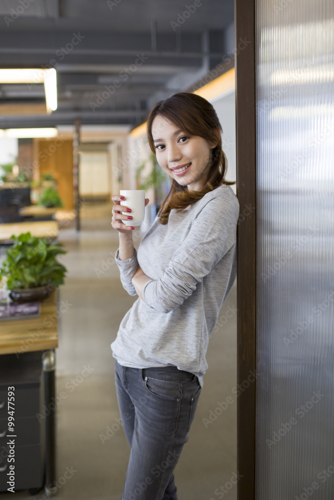 年轻女人在办公室喝咖啡