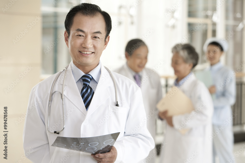 Doctor Holding CAT Scan with Doctors and Nurse in Background