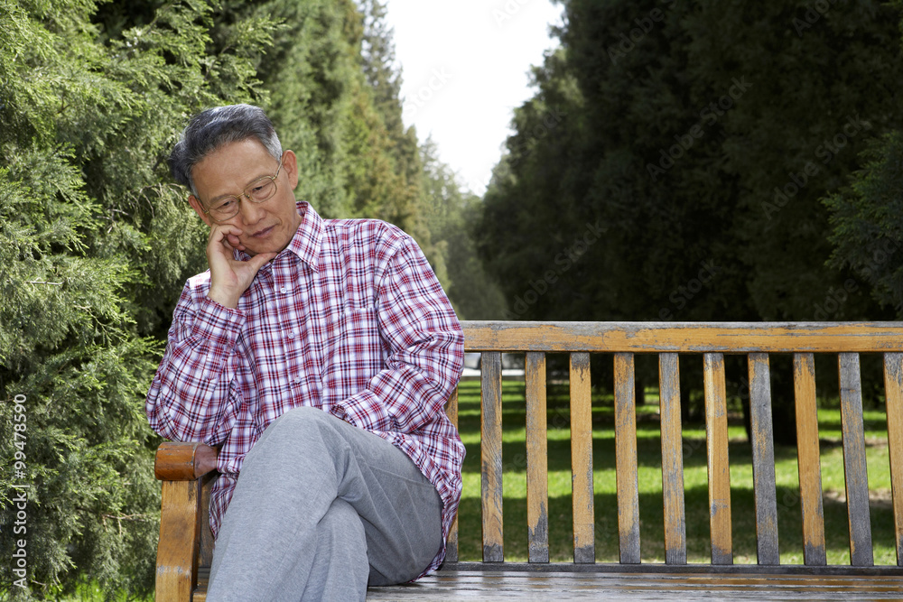 Man Sitting On Park Bench, Looking Thoughtful