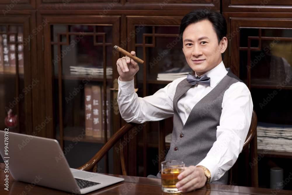 Successful businessman with cigar and drink in hands