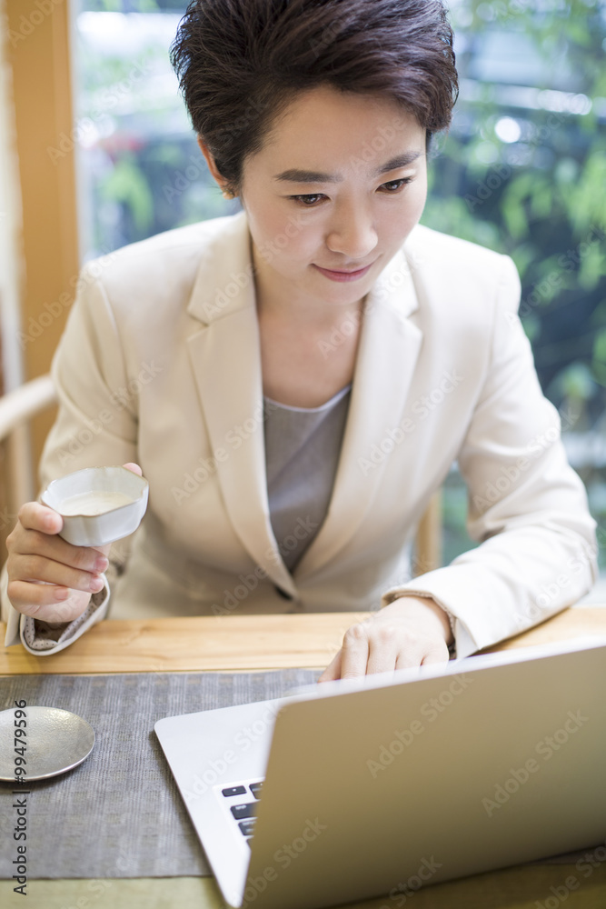 女商人在茶室使用笔记本电脑