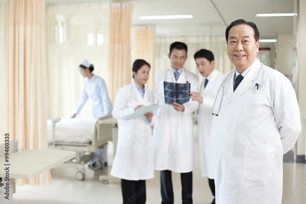 Portrait of  a confident sneior doctor  standing in front of colleagues