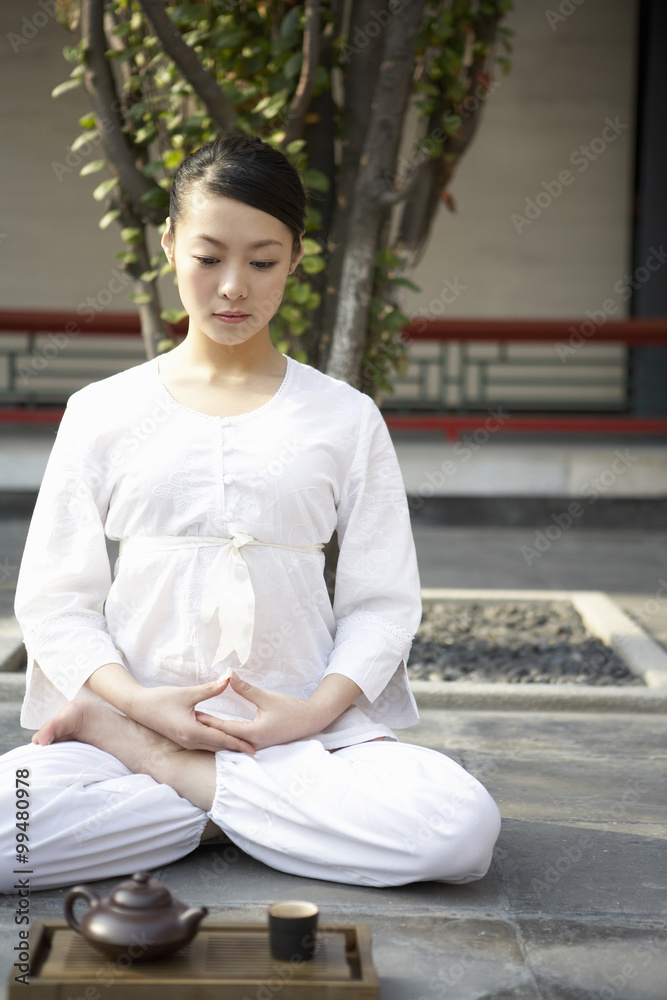 女人在茶具旁盘腿冥想