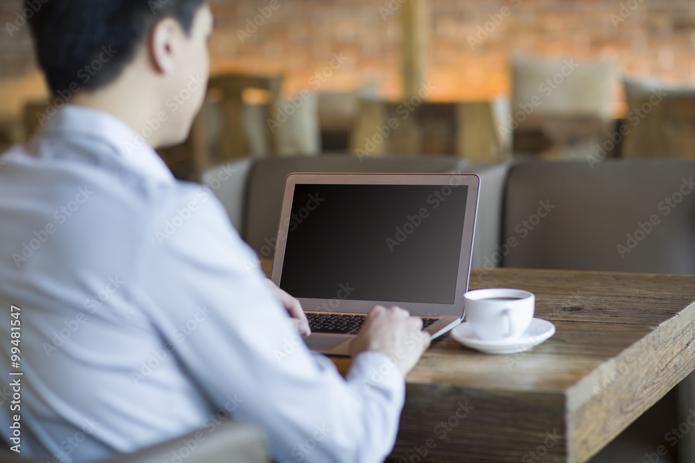 Young man using laptop in cafe