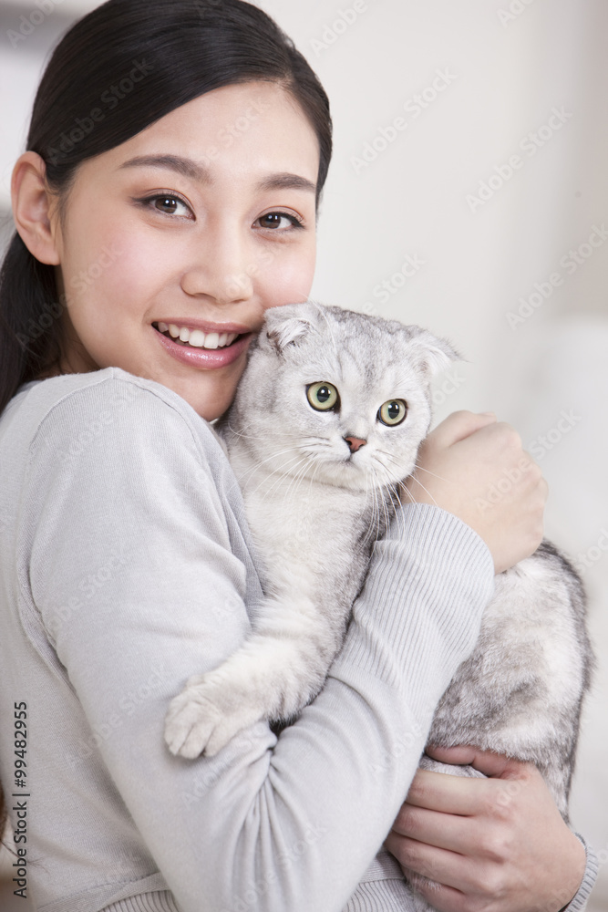 年轻女子与苏格兰折叠猫玩耍