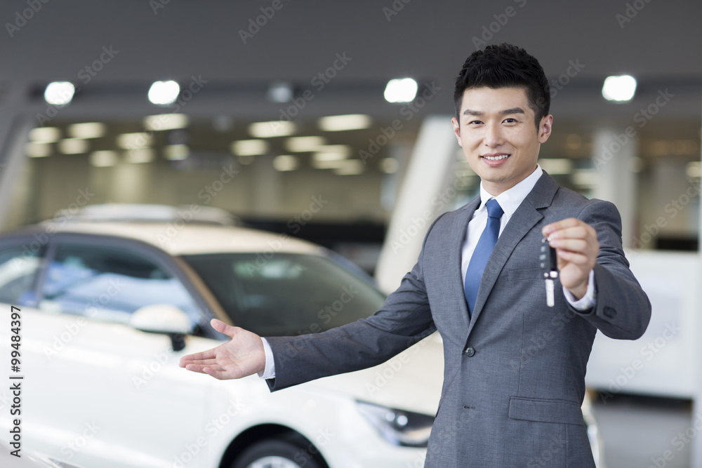 Confident salesman standing with new cars in showroom