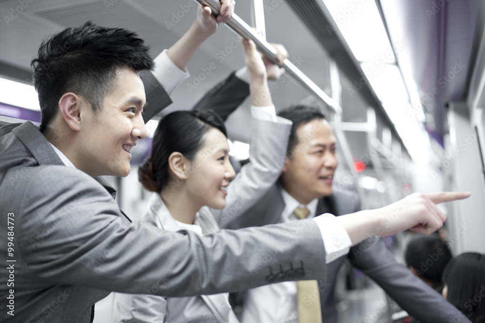 Cheerful business persons pointing outward in subway train