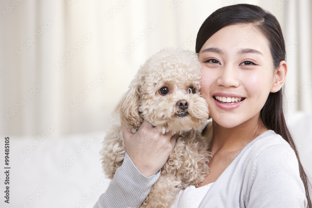 年轻女子与宠物玩具贵宾犬玩耍