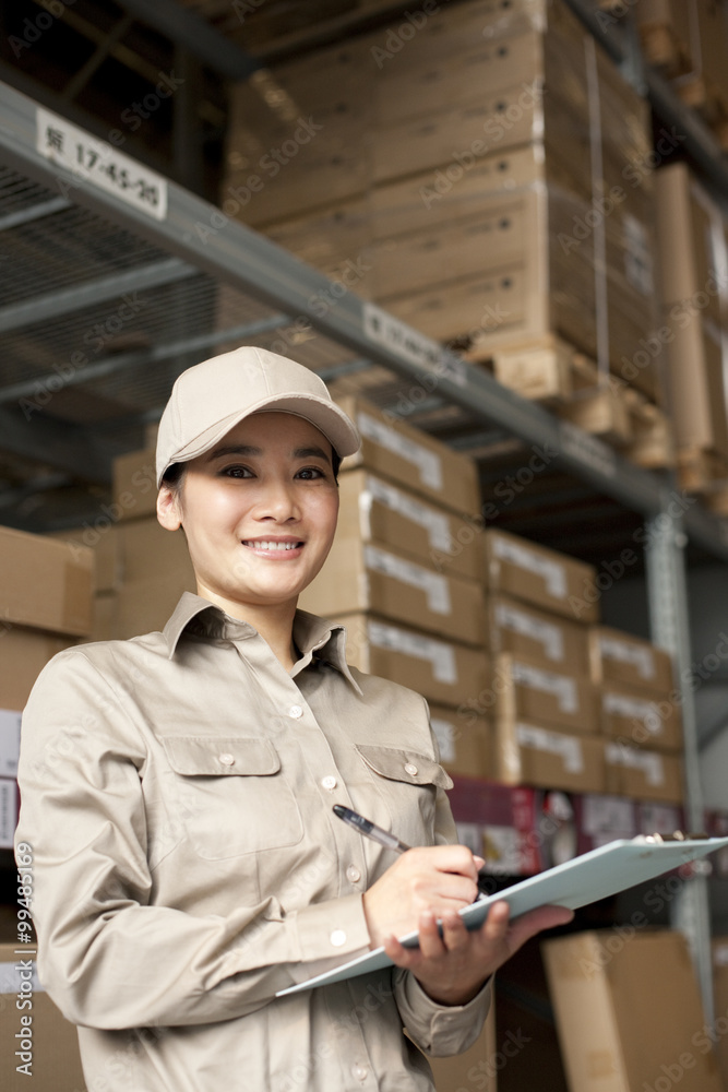 Female Chinese warehouse worker with clipboard