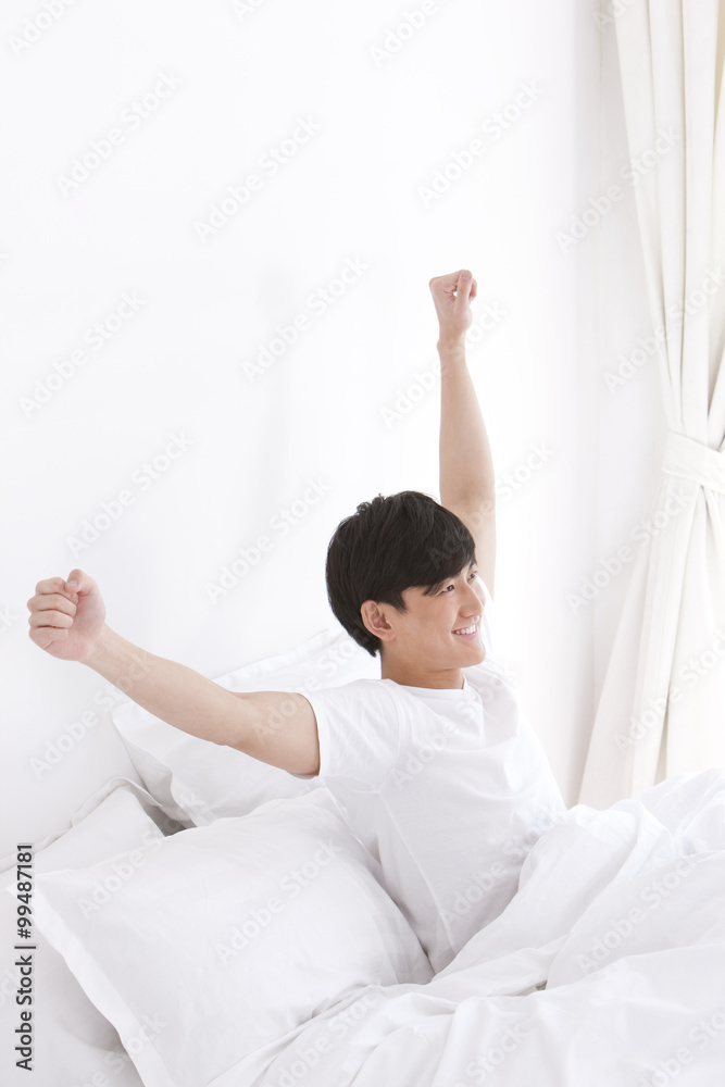 Young man giving a stretch in bed