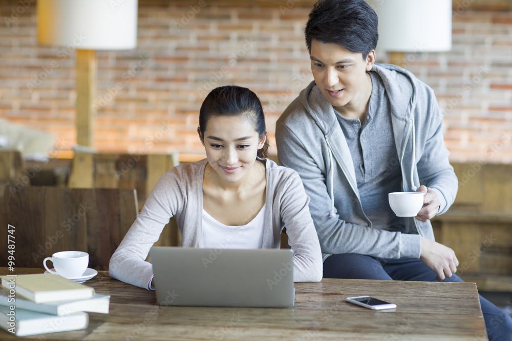 Young couple using laptop in cafe