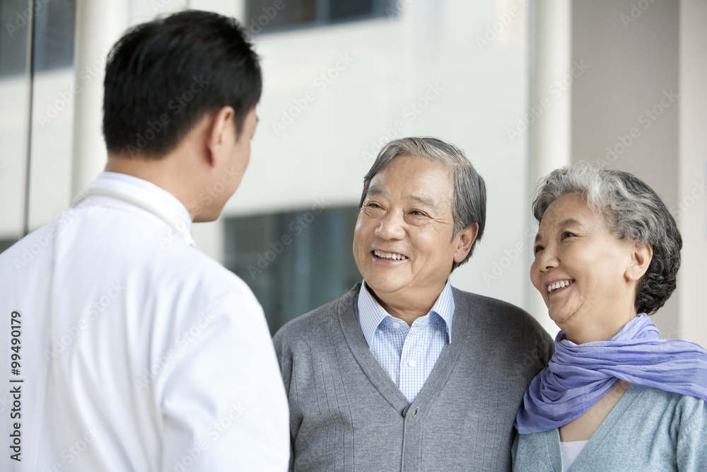 医生在医院走廊与老年夫妇交谈