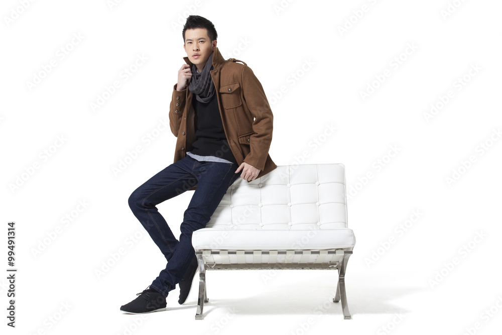 Stylish young man standing by chair