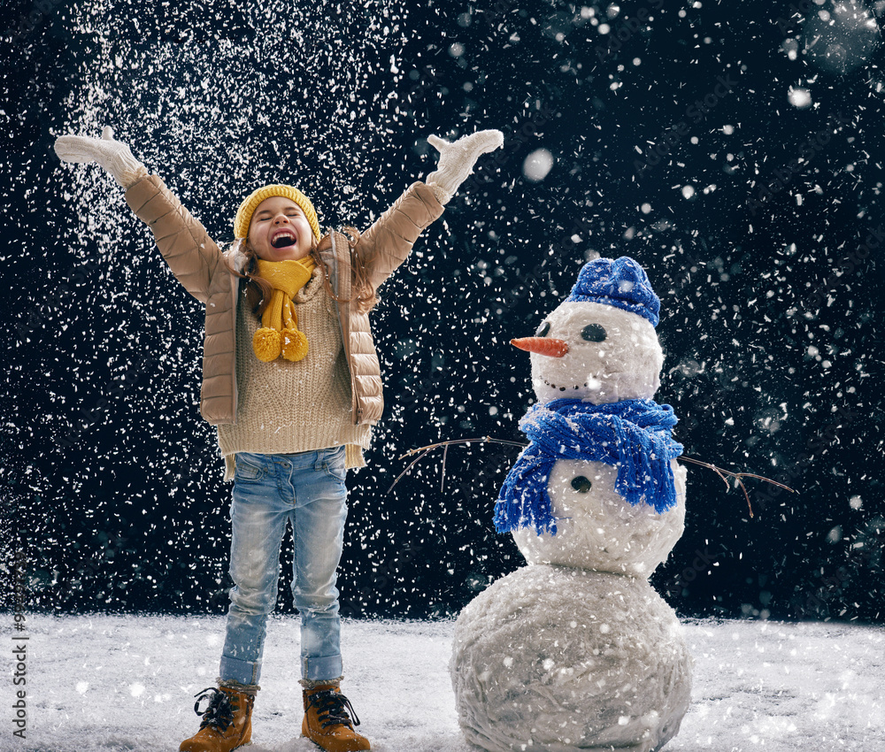 girl plaing with a snowman