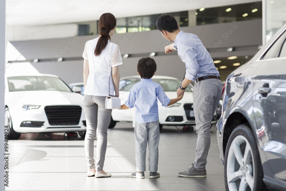 Young family looking at new car in showroom