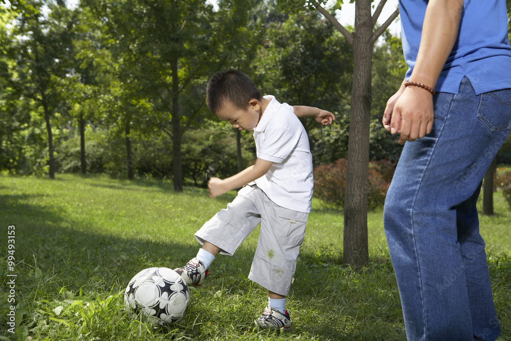 Young Child Playing Soccer In The Park