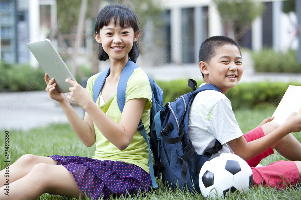 Schoolchildren learning with books and digital tablet