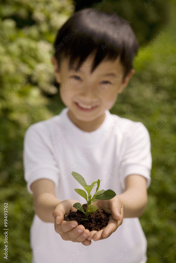 Young Boy Holding Plant In Both Hands