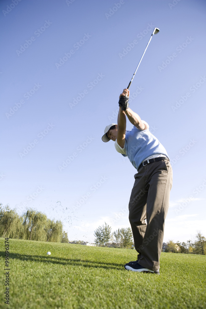 Man swinging golf club on golf course