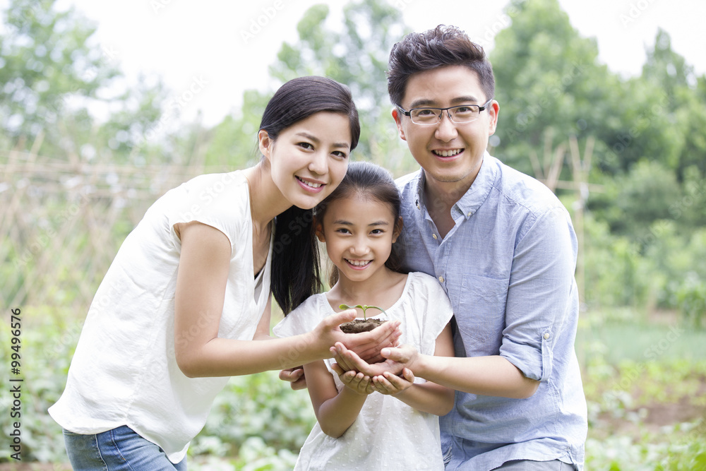 Young family holding a seedling together