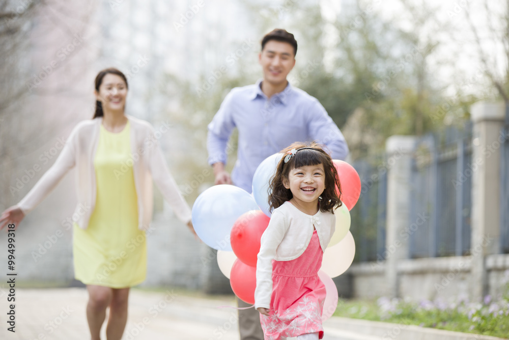 Happy young family running with balloons