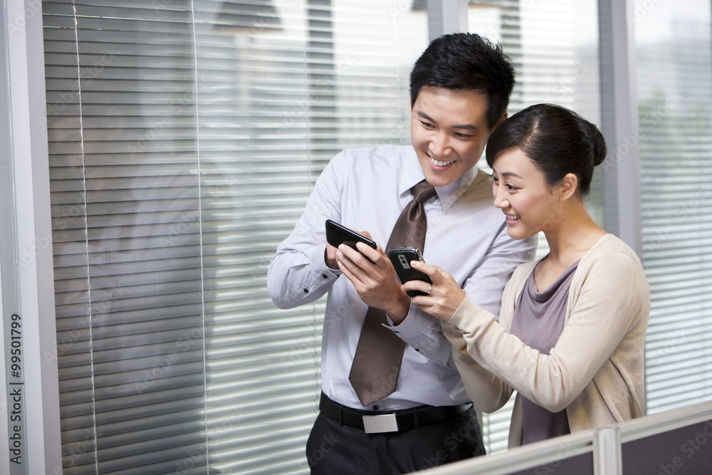 Young Businessman and Businesswoman Comparing Pictures