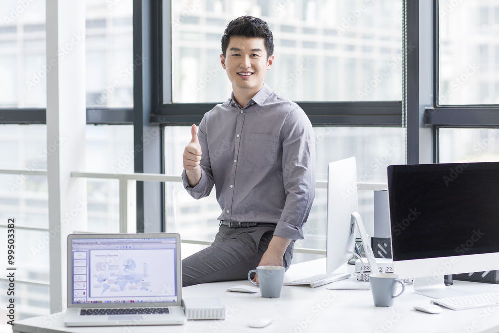 Young businessman giving thumbs up