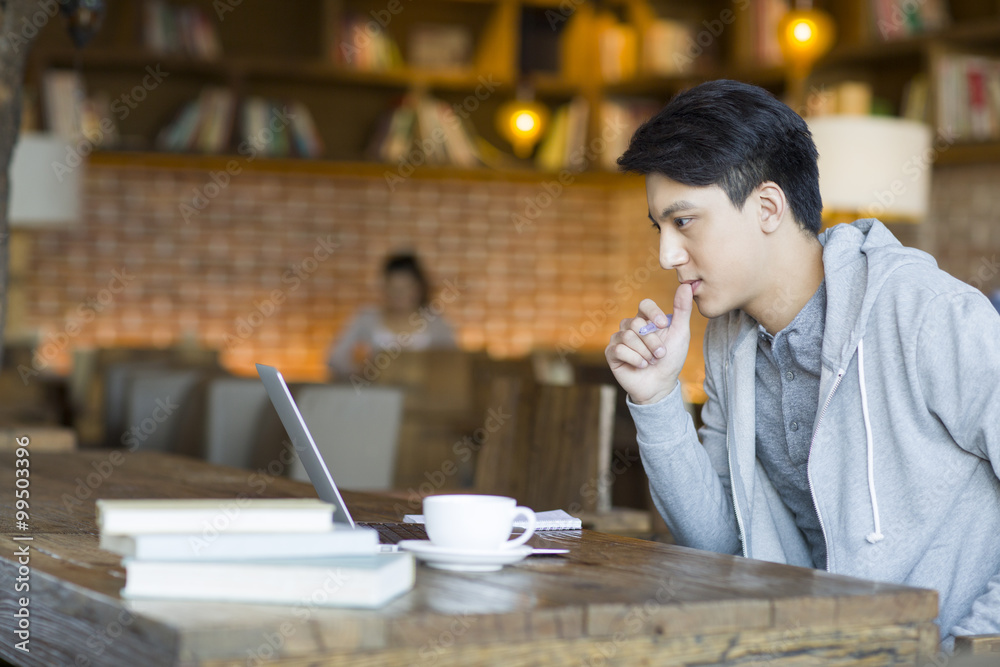 Young man using laptop in cafe