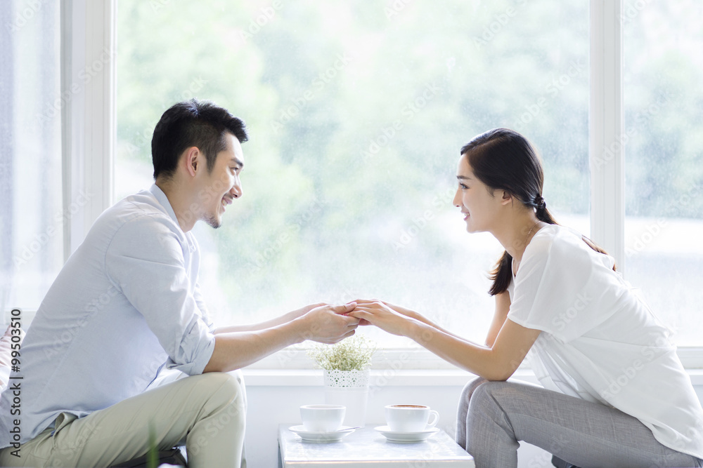 Happy young couple drinking coffee in coffee shop