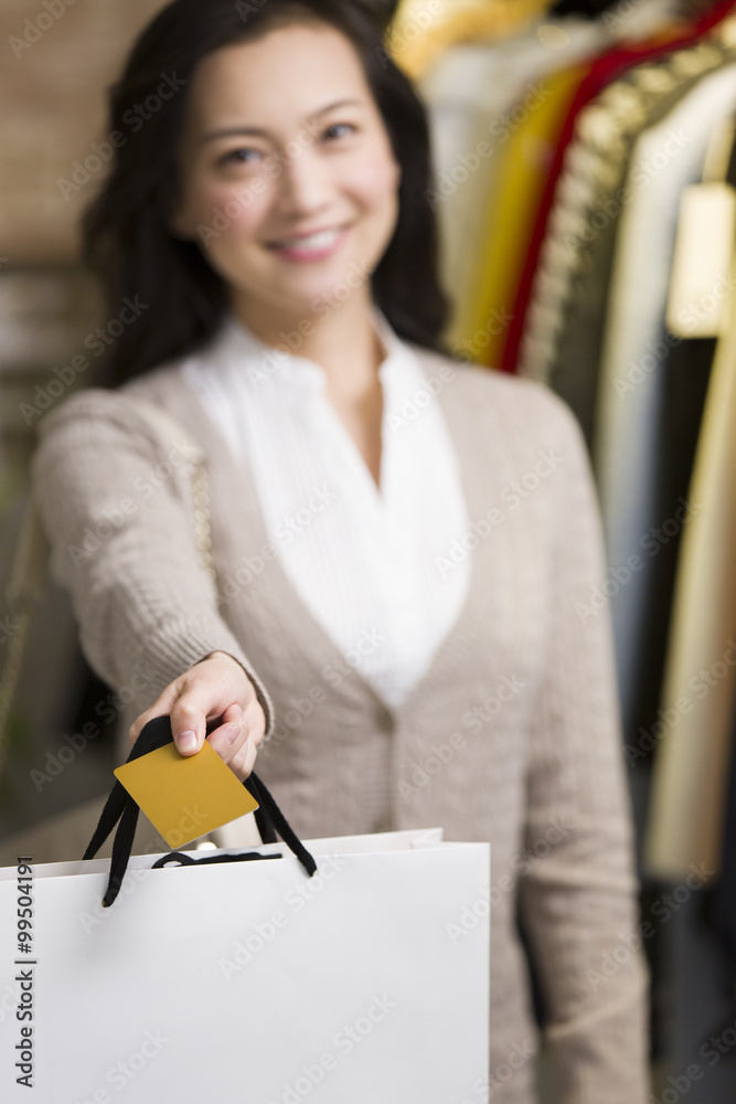 年轻女子在服装店出示信用卡