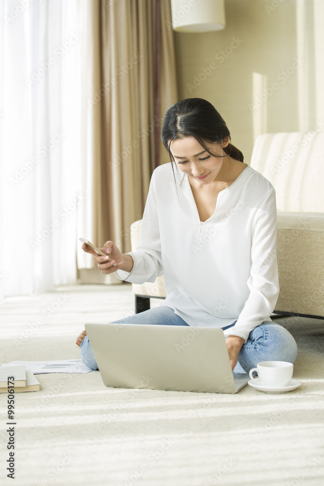 Young woman using smart phone and laptop at home