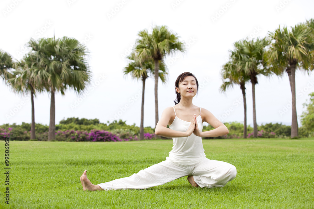 A woman practicing yoga on a grass field