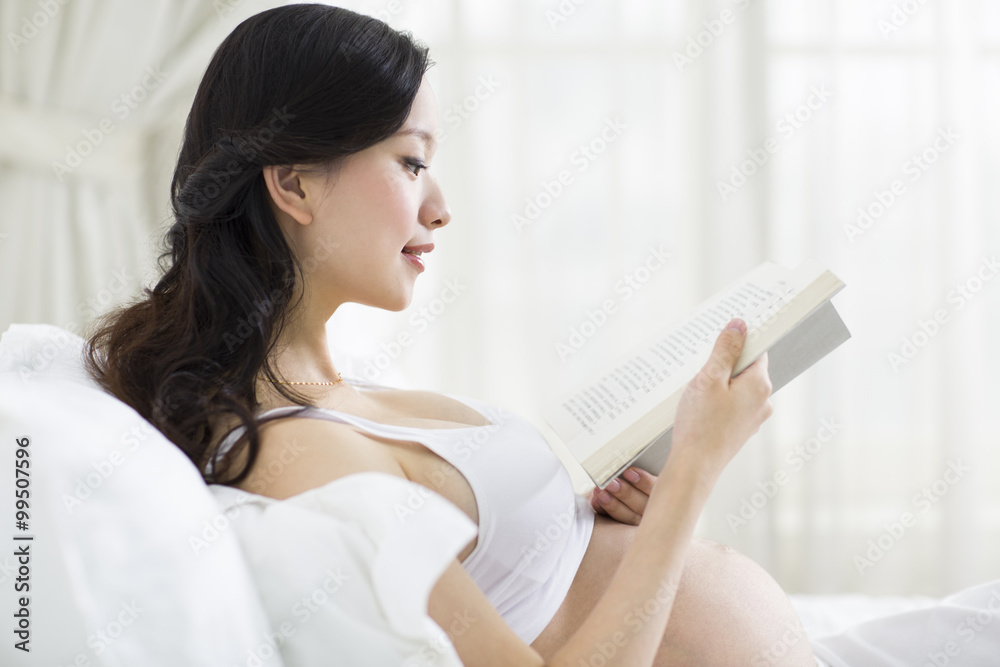 Pregnant woman reading in bed