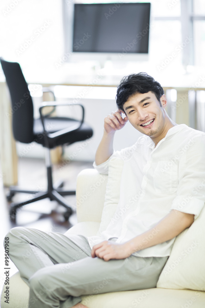 Portrait of young man sitting on sofa