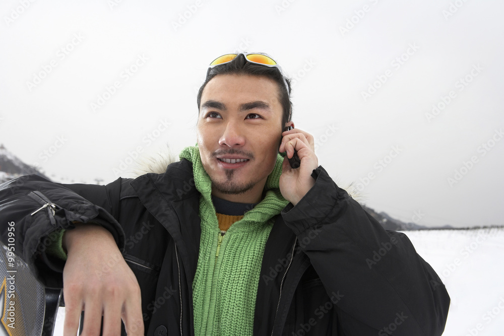 男人在手机上说话，站在滑雪场上