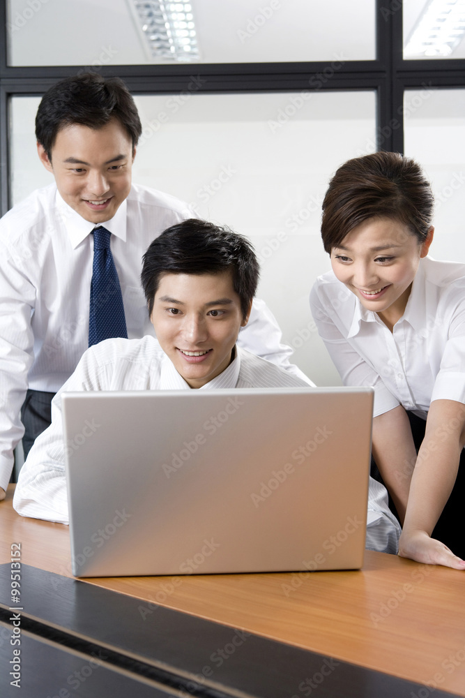 Young businessmen and businesswoman using laptop in office