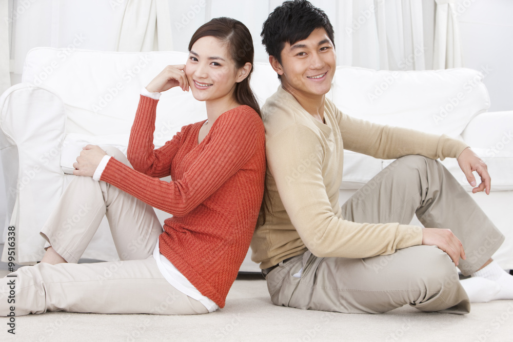 Happy young couple sitting on carpet