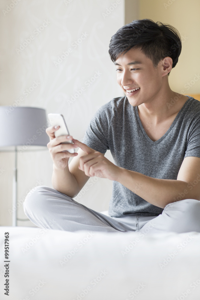 Young man using smart phone on bed