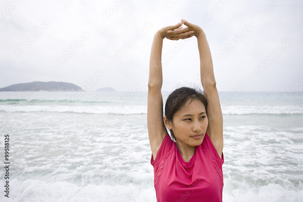 Young woman stretching by the sea