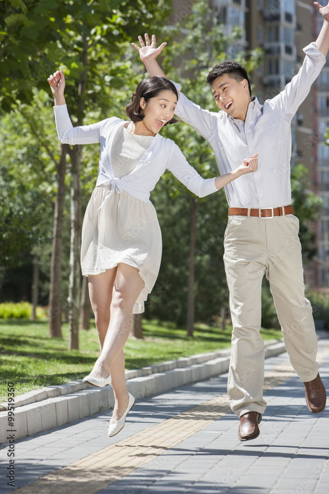 兴奋的年轻夫妇在户外半空中跳跃