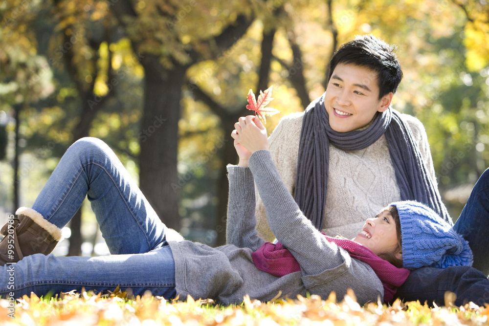 Young Couple in the Park Looking at a Maple Leaf