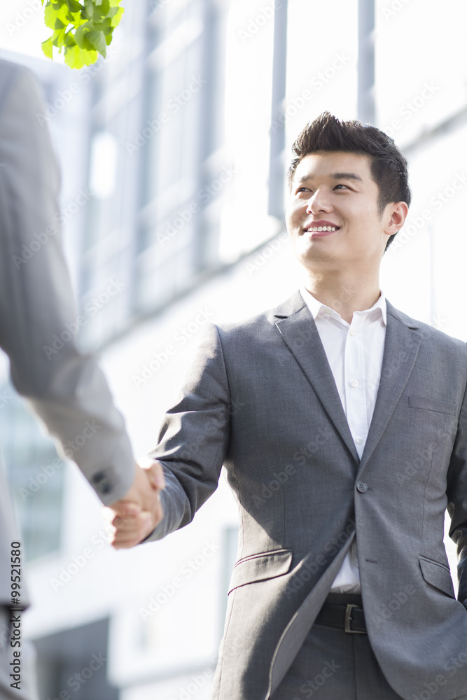 Young business person shaking hands outdoors