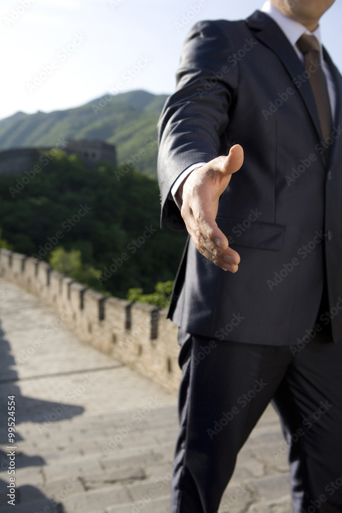 Businessman holding out a hand while on the Great Wall