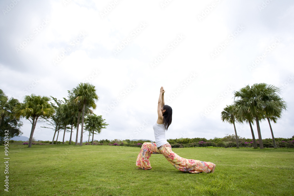 Young woman doing yoga in grass