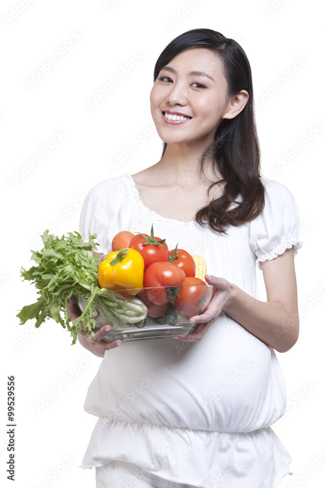 Pregnant woman holding a bowl of fresh vegetables