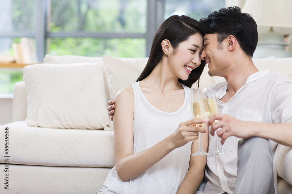 Cheerful young couple drinking champagne in living room