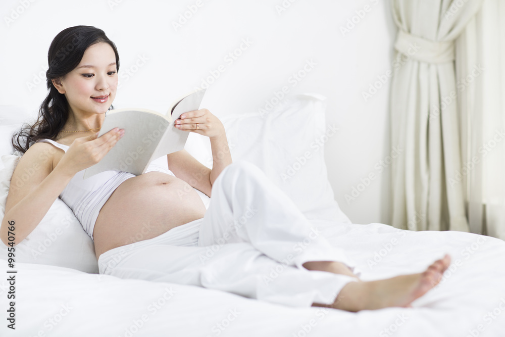 Pregnant woman reading in bed